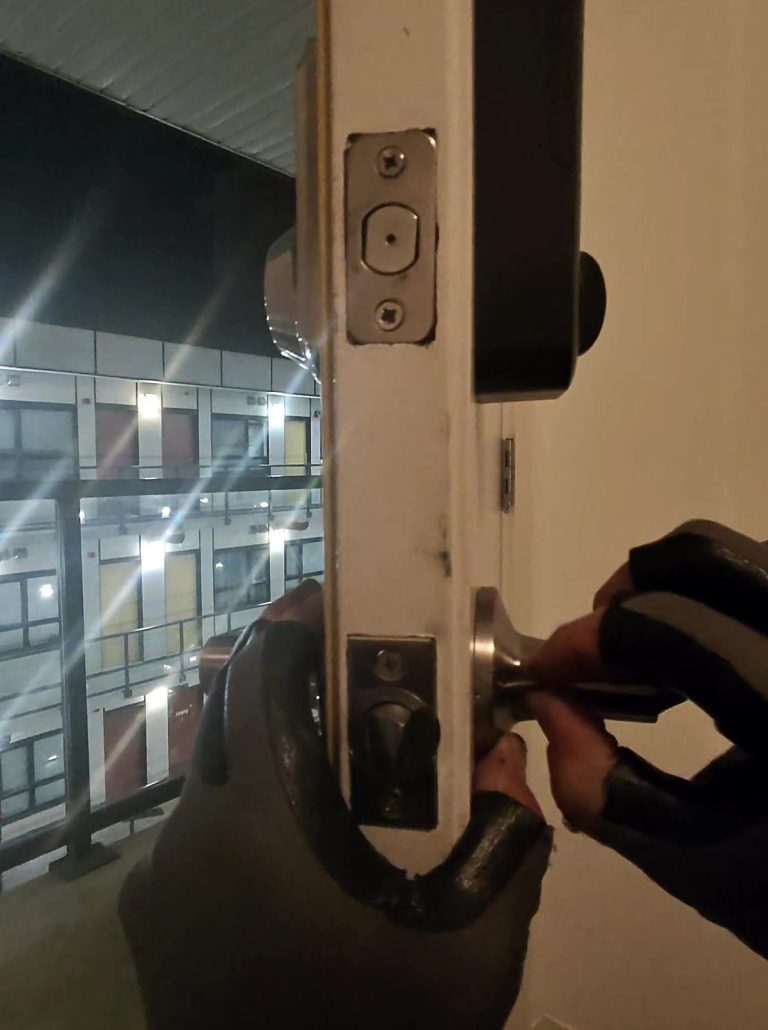 New deadbolt and lever handle being fitted to a condo suite entry door in the evening