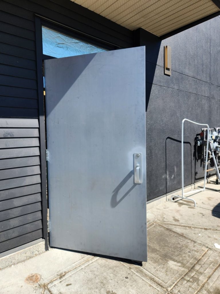 New grey hollow metal service door installed with mortise lock trim at a commercial building
